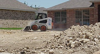 This picture shows a worker beginning to level the ground for the driveway.