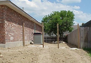 The fence posts have been installed on the right side of the house.