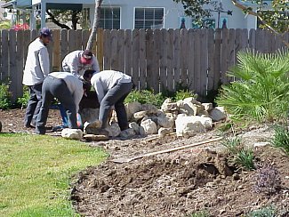 Workers move additional rocks into the landscape.