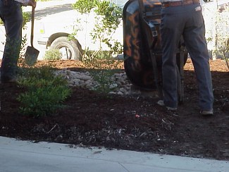 The workers above are using a wheelbarrow to fill a path in the front yard with river rock.