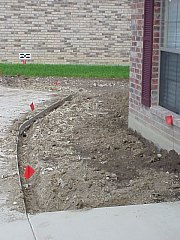 This picture of one of the front planting beds shows where the pipes for the sprinkler system will be placed.  