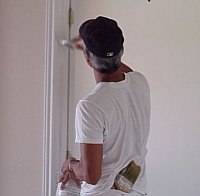 A workman applies a second coat of paint to the door frame.